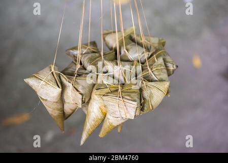 ZhongZi - traditional Chinese rice dish made of glutinous rice stuffed and wrapped in bamboo leaves hanging in the street Stock Photo