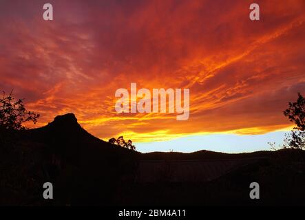 A fiery sunset creates dramatic colors over the silhouette of Thumb Butte. Stock Photo