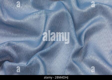 Creased blue curved cloth material fragment with swirl as fabric background texture Stock Photo