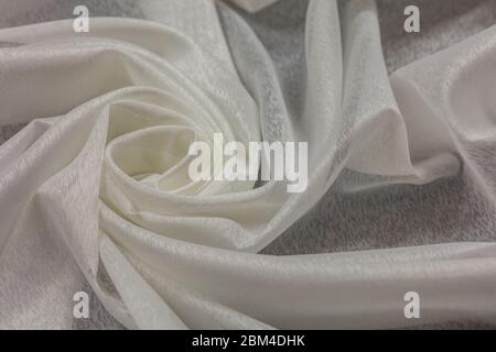 Creased white curved cloth material fragment with swirl as fabric background texture Stock Photo