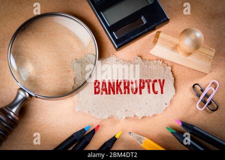 BANKRUPTCY concept. Magnifying glass, stationery and note paper on the table Stock Photo