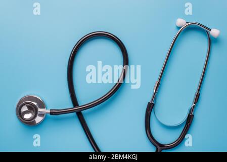 Healthcare concept. Top above overhead flatlay close up photo of black stethoscope phonendoscope isolated on pastel blue background Stock Photo