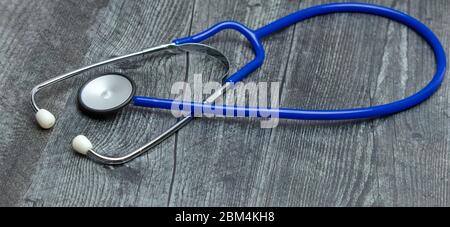 A blue medical stethoscope isolated on a wooden table. Stock Photo