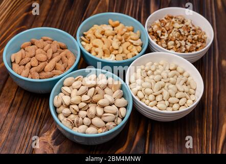Healthy food and snack. Walnuts almonds, pistachios, cashews, peanuts on a wooden board. Group of mixed nuts. Top view Stock Photo