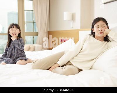 young asian mother pretending to be unhappy while cute daughter laughing Stock Photo