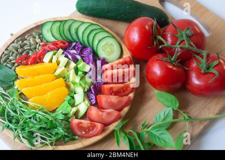 A buddha bowl of fresh summer healthy rainbow salad with cucumbers, tomatoes, arugula, basil, pumpkin seeds, avocado, red cabbage and chili pepper on Stock Photo