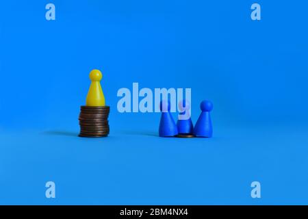 Pawns standing on piles of different sizes of coins. Income and economic inequality concept. Stock Photo