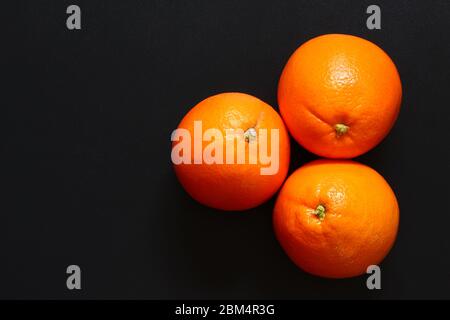 Three healthy oranges together on a dark surface, with copy space Stock Photo