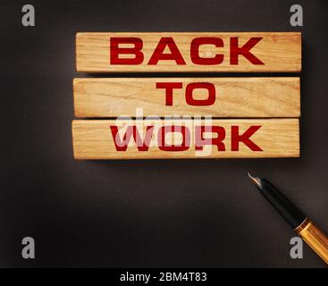 Words back to work written with wooden blocks on black background and luxury pen besides. Business concept Stock Photo