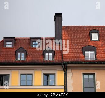 Close-up of  houses with red tile roof, chimney, attic, windows and downspout in Munich, Germany Stock Photo