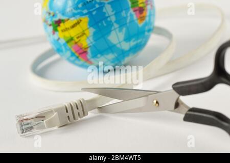 Scissors cutting internet cable with planet earth on white background - Concept of global internet outage Stock Photo