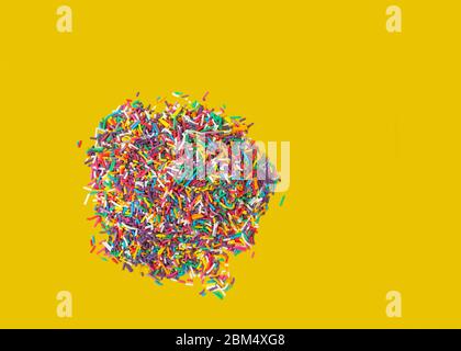 Cake decoration sprinkles in a white bowl isolated on a yellow background with copy space Stock Photo