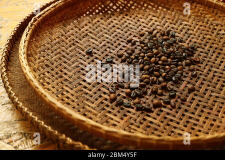 Close up of  dark roasted coffee beans on wicker basket before sieving for home-brew coffee Stock Photo
