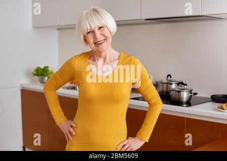 Grey hair woman standing in kitchen at home Stock Photo