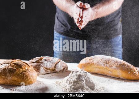 Baker cooking bread. Man slaps flour. Food concept. Stock Photo