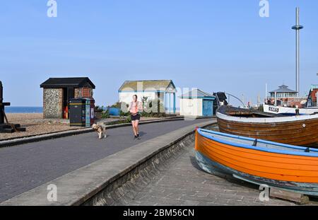 Brighton UK 7th May 2020 - A young woman and her dog run by Brighton Fishing Museum on a beautiful sunny morning during the Coronavirus COVID-19 pandemic crisis . The weather is forecast to be hot and sunny over the next few days before turning cooler at the weekend . Credit: Simon Dack / Alamy Live News Stock Photo