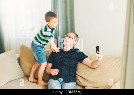 Father and son communicate online by phone with relatives or friends. Online communication, remote communication. Online call friends. Stock Photo