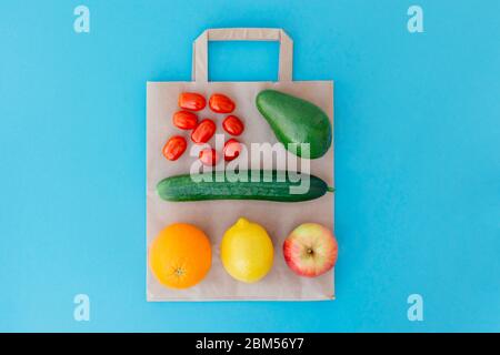 Fruits and vegetables on a paper bag on blue background. Concept healthy food. Food delivery, online shop. Buy products online during quarantine. Stock Photo