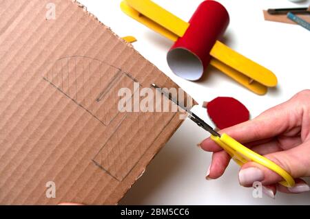 How to make airplane. Hand made toy,zero waste from toilet paper roll and popsicle sticks. For kids and parents. Step 13 cut tail of airplain Stock Photo