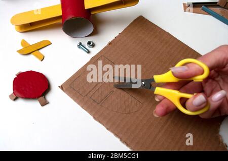 How to make airplane. Hand made toy,zero waste from toilet paper roll and popsicle sticks. For kids and parents. Step 12 draw details for tail. Stock Photo