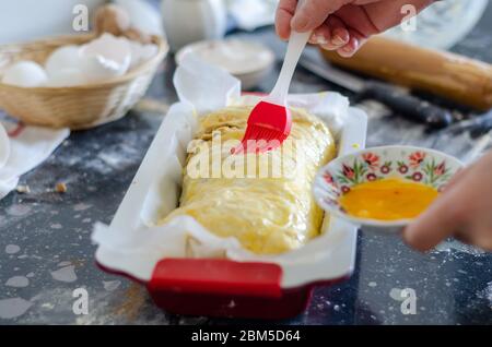 The woman is applying eggs yolk  on bakery,  close-up Stock Photo