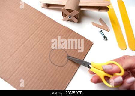 How to make airplane. Hand made toy,zero waste from toilet paper roll and popsicle sticks. For kids and parents. Step 15 cut out circle. Stock Photo