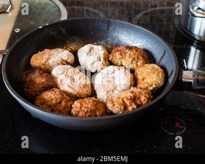 many russian Kotleta (minced beef steaks breaded with flour) in hot pan on ceramic stove at home kitchen Stock Photo