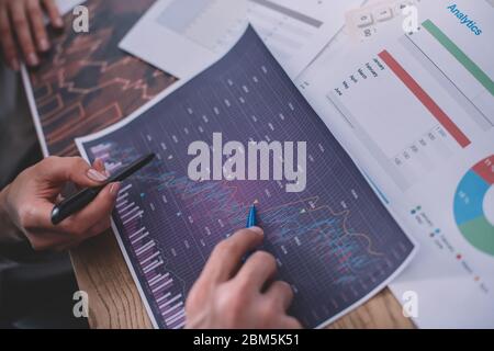 Cropped view of data analysts working with charts and papers on table Stock Photo