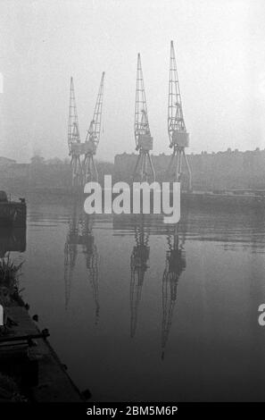 Bristol in the Sixties: A foggy day close to Bristol Cathedral in November 1968.  A view of Bristol Docks looking from the Canons Marsh side near the gas works across the Floating Harbour to an area near Princes Wharf.  The docks remained in action using electric cranes built in Bath through the 60s up until the last regular cargo shipment in 1974. Stock Photo