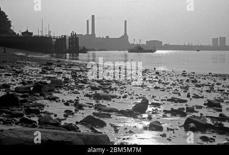 Historic London:  Low water on the River Thames near Greenwich Pier on a summer’s evening in July 1969.  In the background, the coal-fired Deptford Power Station, site of the first modern high-voltage power station in the world.    At one time the second largest station in Britain, the final chimney came down in 1992 and the site is now part of the Millennium Quay development, which includes more than 600 apartments. Stock Photo