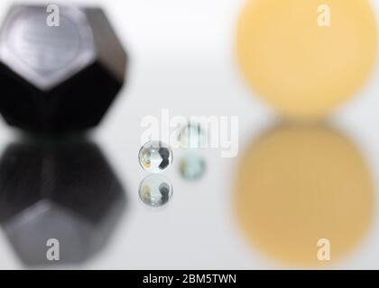 A marble in the first in the centre of the image is reflected on a glossy surface, in the background you can see other geometric shapes. Stock Photo
