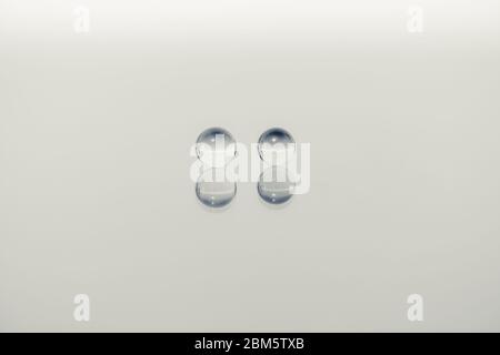 Two small marbles side by side are resting on a reflective background of light color, treatment of the colours of the monochromatic image. Stock Photo
