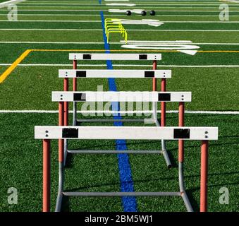 Mini and regular hurdles are set up on a green turf field for speed and agility practice. Stock Photo