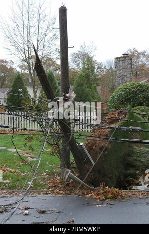 A telephone pole with electric wires breakes in half and falls during super storm sandy on long island Stock Photo