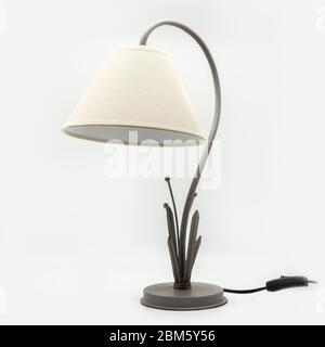 A modern table lamp with a beige lampshade and a metal base, cut out on white background Stock Photo