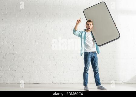 Excited man having idea while holding model of smartphone at home Stock Photo