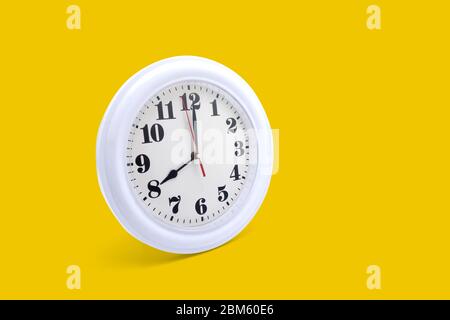 Modern wall clock white isolated on yellow background, time and period, office timepiece and mockup with hour and minute, hour hand, object classic. Stock Photo