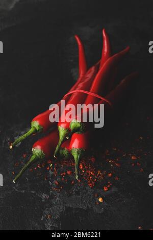 Tasty chilli peppers on black cement background Stock Photo