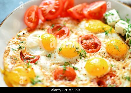 Fried quail eggs in a beautiful plate on a dark table background. Fried eggs with tomatoes and dill. Tasty and healthy breakfast. Close-up. Fried eggs Stock Photo
