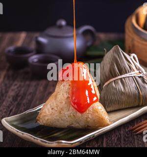 Zongzi - Chinese rice dumpling zongzi in a steamer on wooden table black retro background for Dragon Boat Festival celebration, close up, copy space. Stock Photo