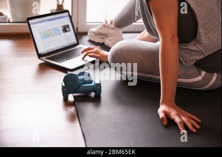 Training, Fitness At Home. Sporty man doing yoga plank while watching online tutorial on laptop, exercising in living room. woman multitasking remote work indoors lifting weights dumbbells. Stock Photo