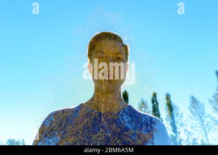 Multiple exposure of young handsome man overlaying oak tree and sun against blue sky Stock Photo