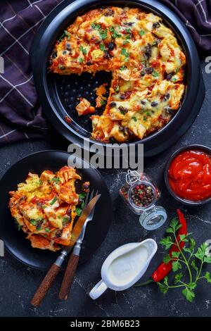 Tamale pie or pulled chicken casserole with corn crust,  cheddar cheese, black bean filling on a black baking dish, served on a wooden background with Stock Photo