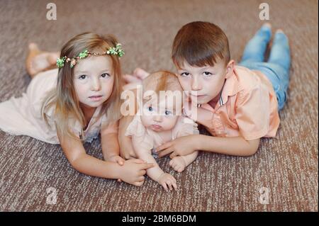 Little Children Together Hangout and Smiling in studio on floor. Brother and two sisters Stock Photo