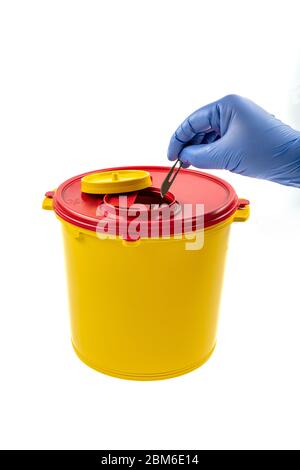 Closeup of hand depositing a used lancet on waste needle container. Health worker throws sharp waste into the medical waste bin. Medical Waste Rubbish Stock Photo