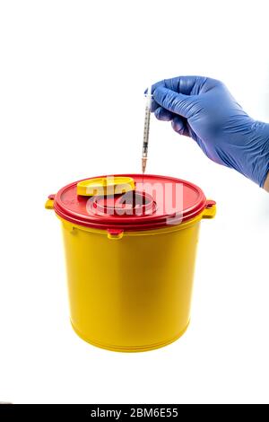 Closeup of hand depositing a used lancet on waste needle container. Health worker throws sharp waste into the medical waste bin. Medical Waste Rubbish Stock Photo