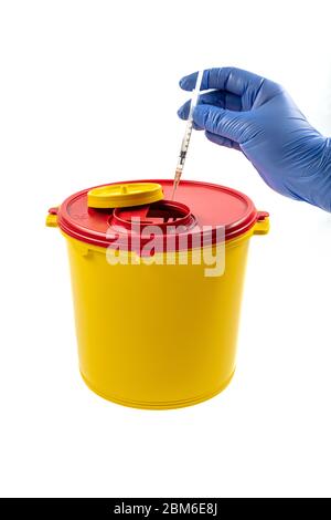 Closeup of hand depositing a used lancet on waste needle container. Health worker throws sharp waste into the medical waste bin. Medical Waste Rubbish Stock Photo