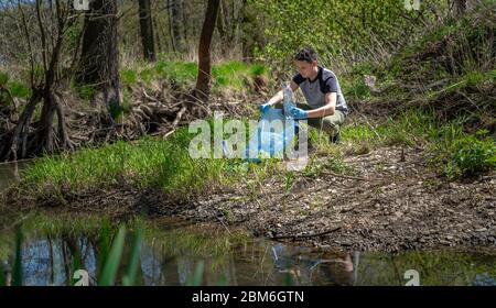 cleaning of plastic waste on the river bank by a volunteer. Helping nature and protecting the environment Stock Photo