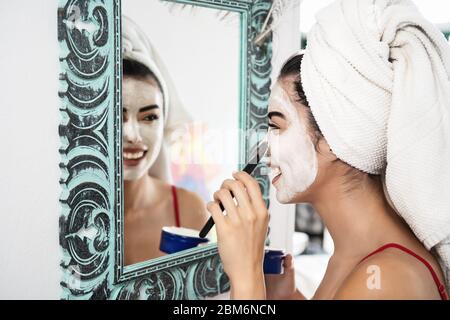Young woman applying daily facial cream - Happy girl having skin care spa day portrait Stock Photo