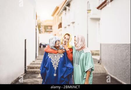 Happy Muslim women walking in the city center - Arabian young girls having fun spending time and laughing together outdoor